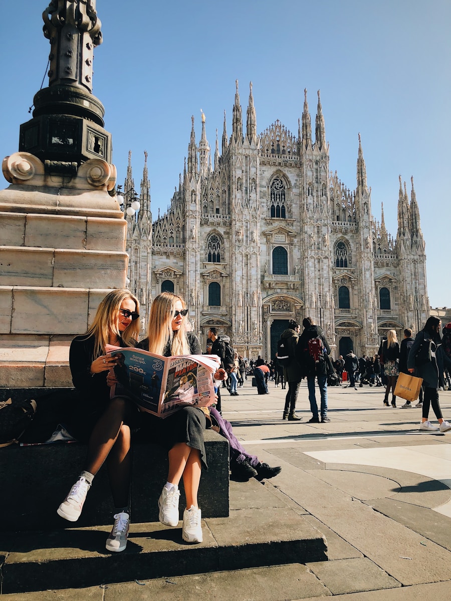 two women sitting on a bench in front of a cathedral